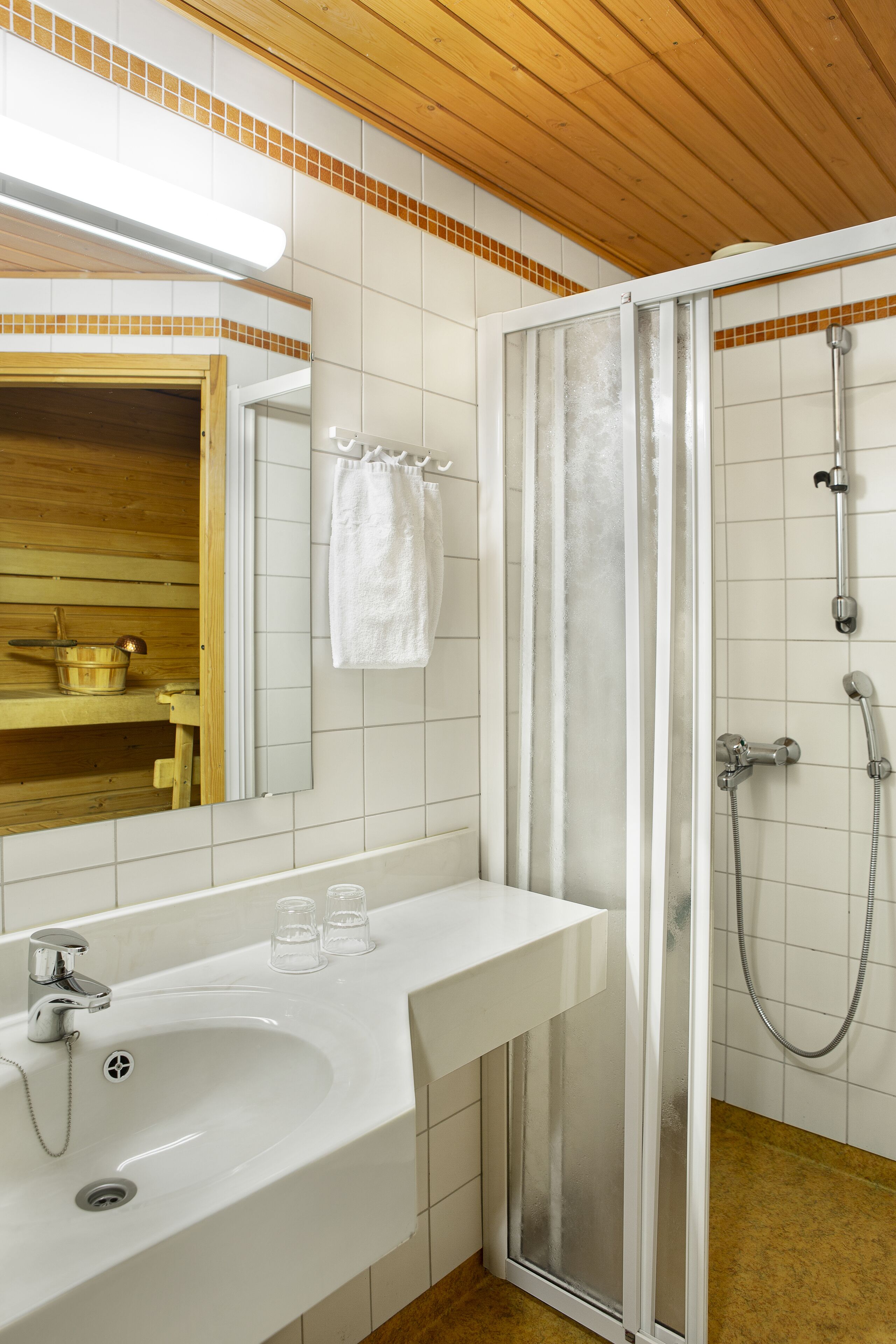 A bathroom with a white sink, mirror, and shower enclosure.