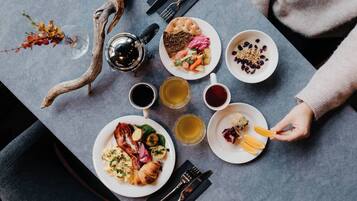 Una mesa dispuesta con diferentes platos, bebidas y una rama decorativa.