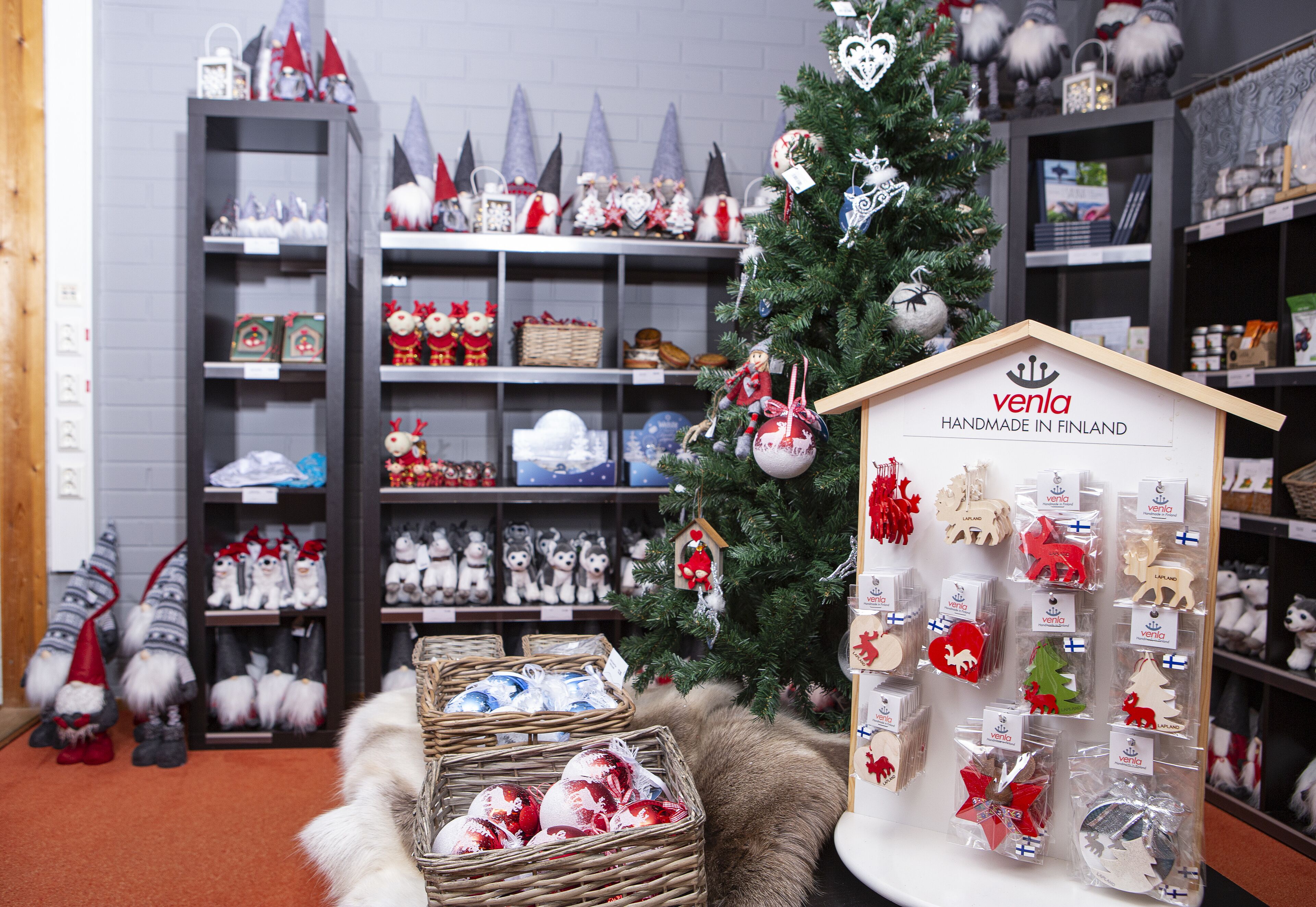 A retail display with various Christmas decorations, including gnomes, ornaments, and a sign indicating the products are handmade in Finland.