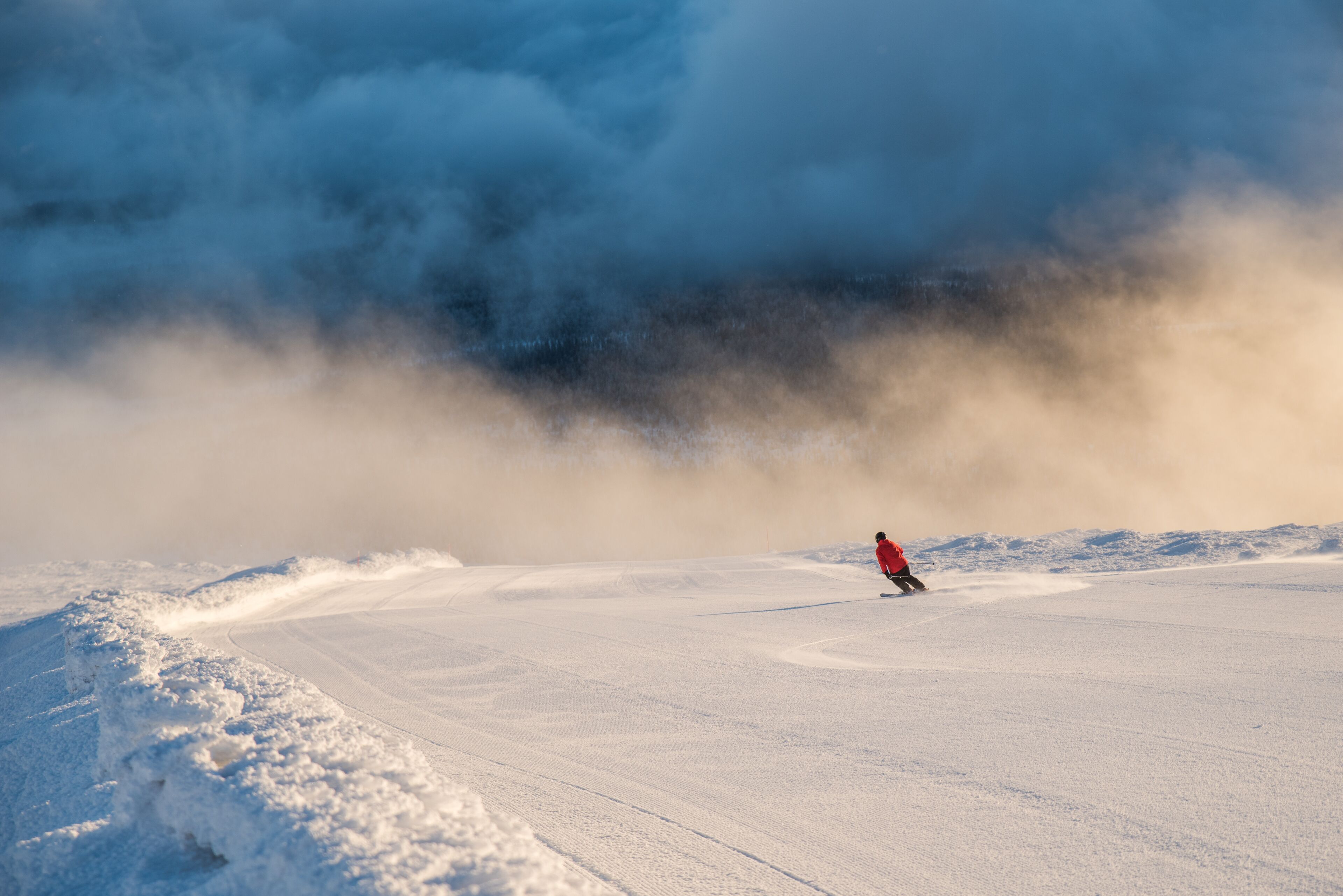 Un paysage enneigé où l’on voit une personne faire du ski.
