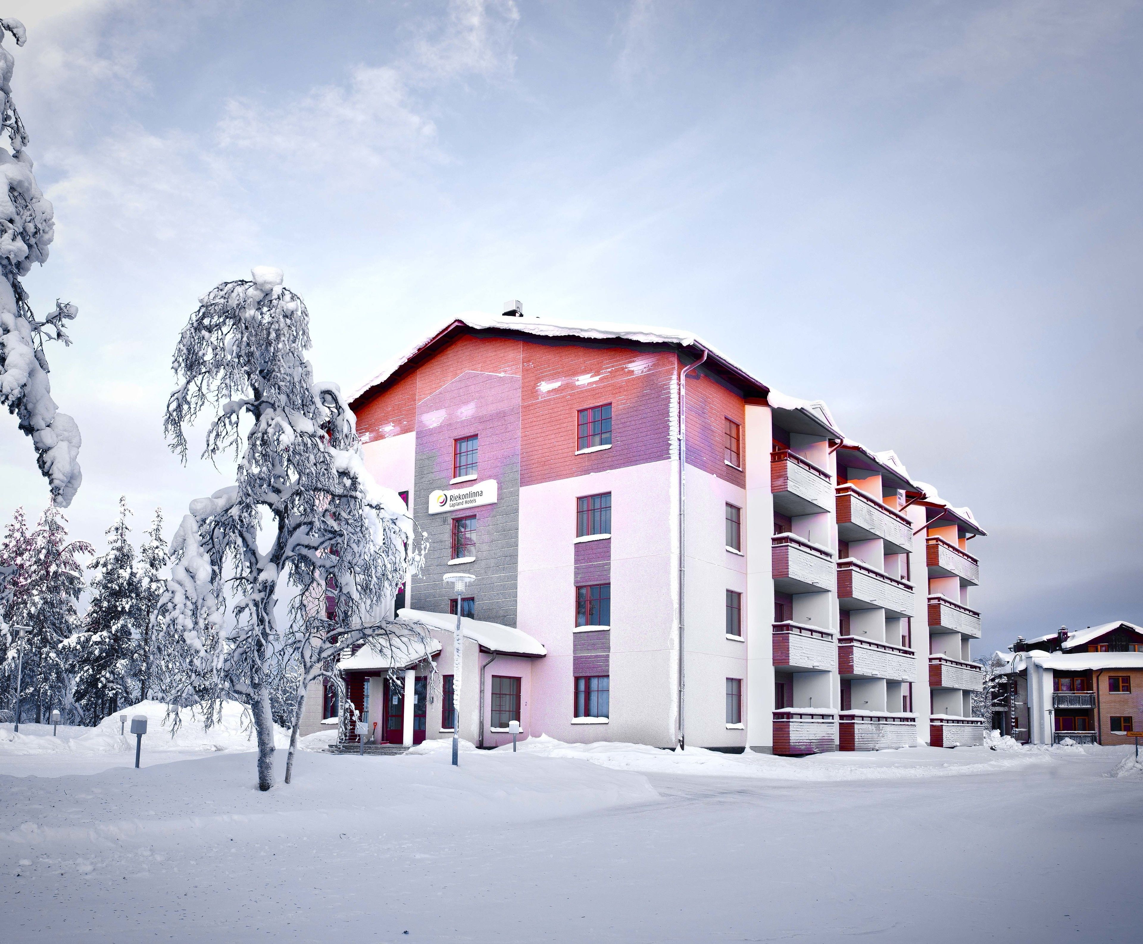 Een meerhoog hotel met een rood-wit gevel, balkons en een besneeerd landschap.