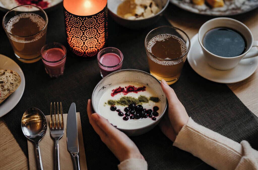 A table setting with a bowl of yogurt topped with berries and a candle.