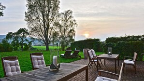 Een terras met een houten tafel en stoelen, een bank en een kaars als decoratie.