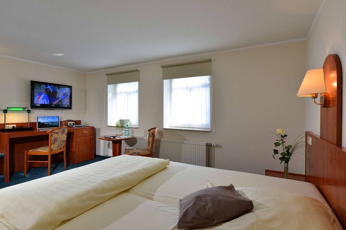 Une chambre d’hôtel équipée d’un lit, d’un bureau, d’une chaise, d’une télévision et d’une fenêtre avec des rideaux.