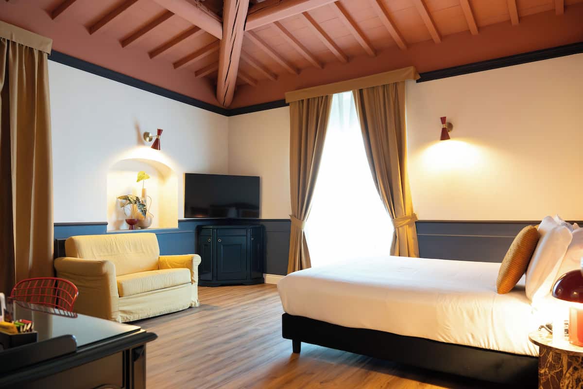 A hotel room with a bed, a sofa, a TV, and a desk.
