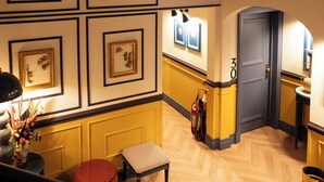 A hotel lobby with framed artwork on the walls, a fire extinguisher, a bench, and a door marked with the number 30. - JOIVY Together Florence Secret Nest (Florence)