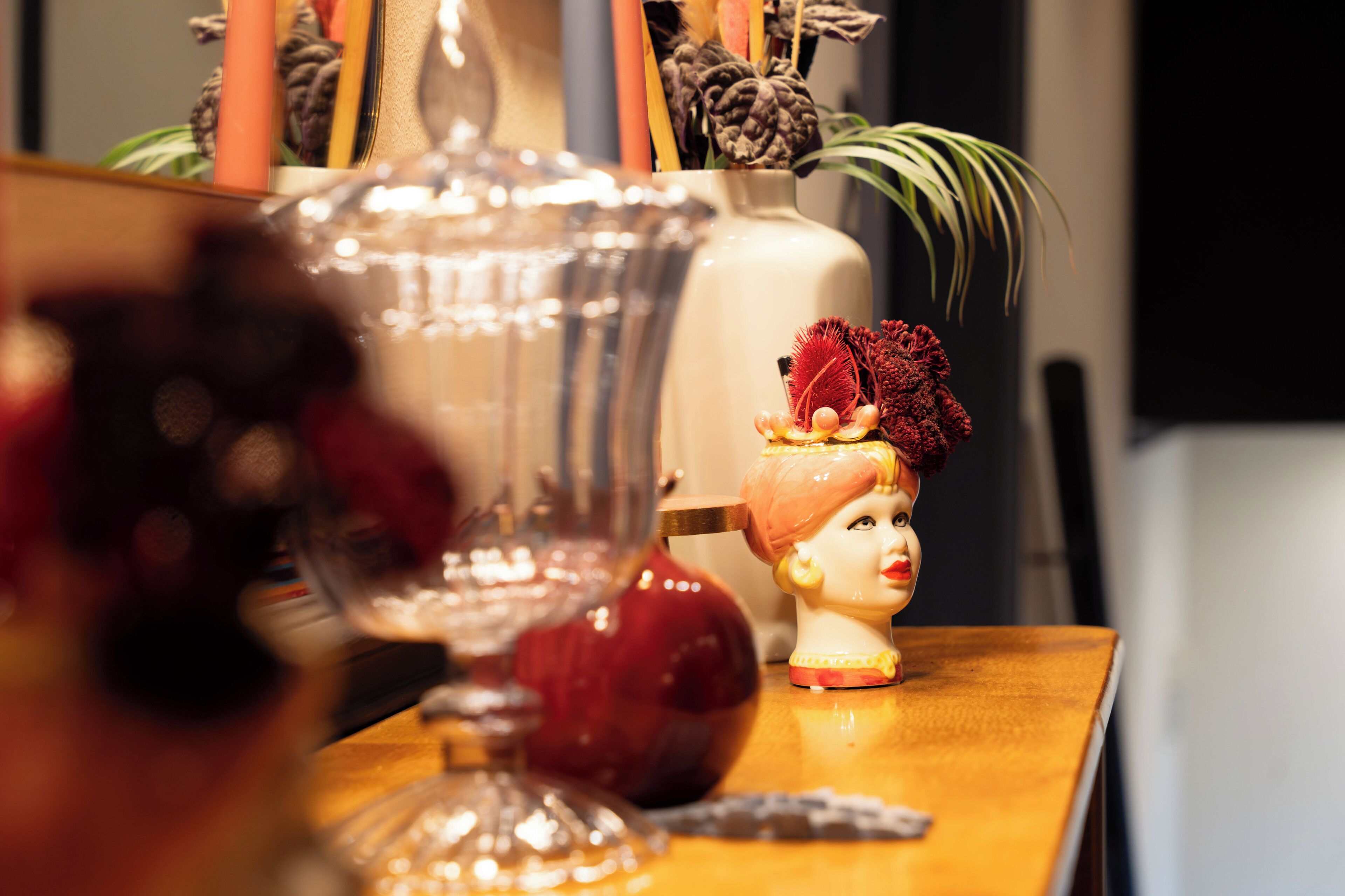 A table with decorative items including a vase, a glass container, and a ceramic head sculpture.