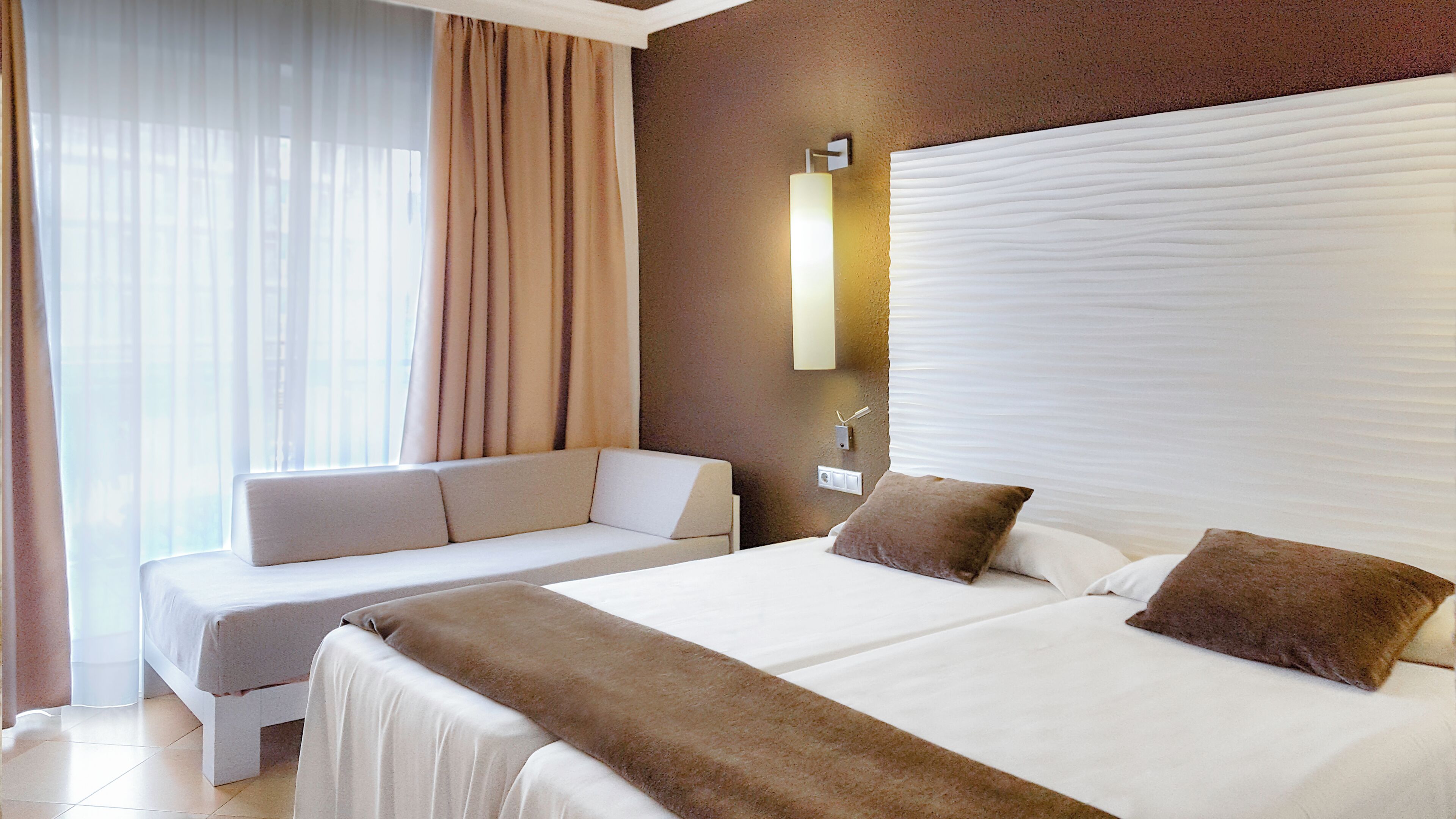 Een hotelkamer met een groot bed, een bank en een raam met gordijnen.