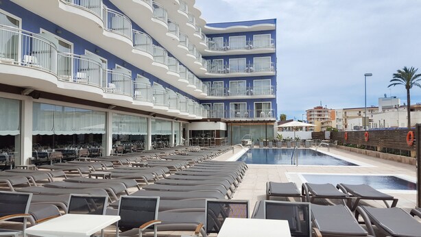A hotel with a pool area, outdoor seating, and a view of the sea. - Hotel Cesar Augustus (Cambrils)