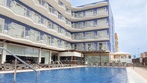 A multi-story hotel with a swimming pool, outdoor seating, and balconies. - Hotel Cesar Augustus (Cambrils)