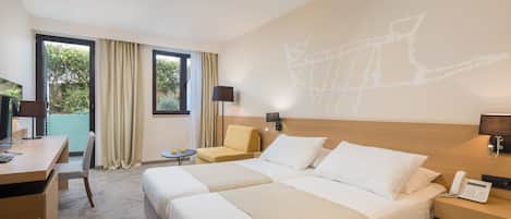 A hotel room with two beds, a desk, a chair, a small table, and a wall-mounted phone.