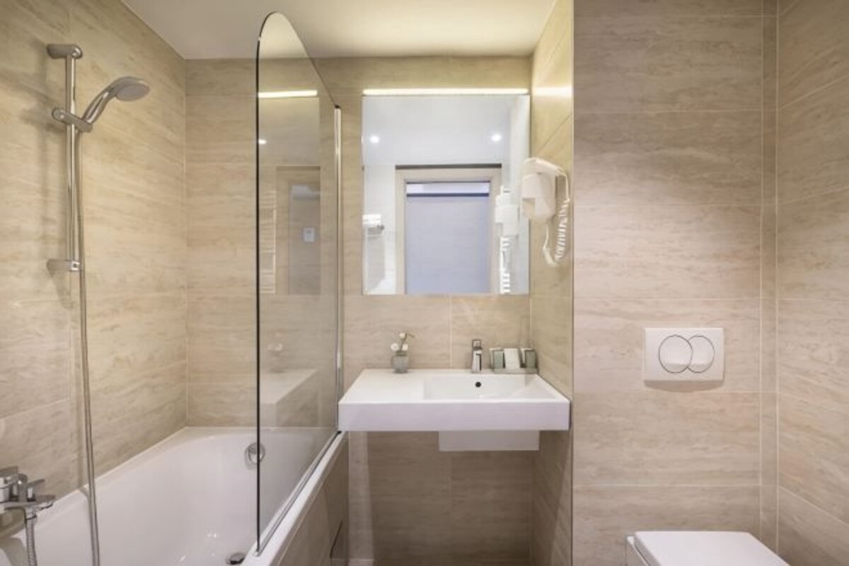 A modern bathroom with a glass-enclosed shower, a white sink, and a mirror above it.