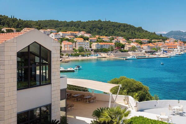 A coastal town with a modern building featuring large windows and a patio area with outdoor furniture.