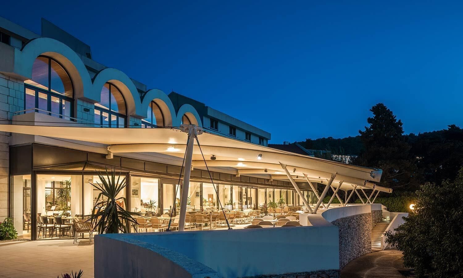 Un edificio moderno con una zona de estar al aire libre techada y grandes ventanales.