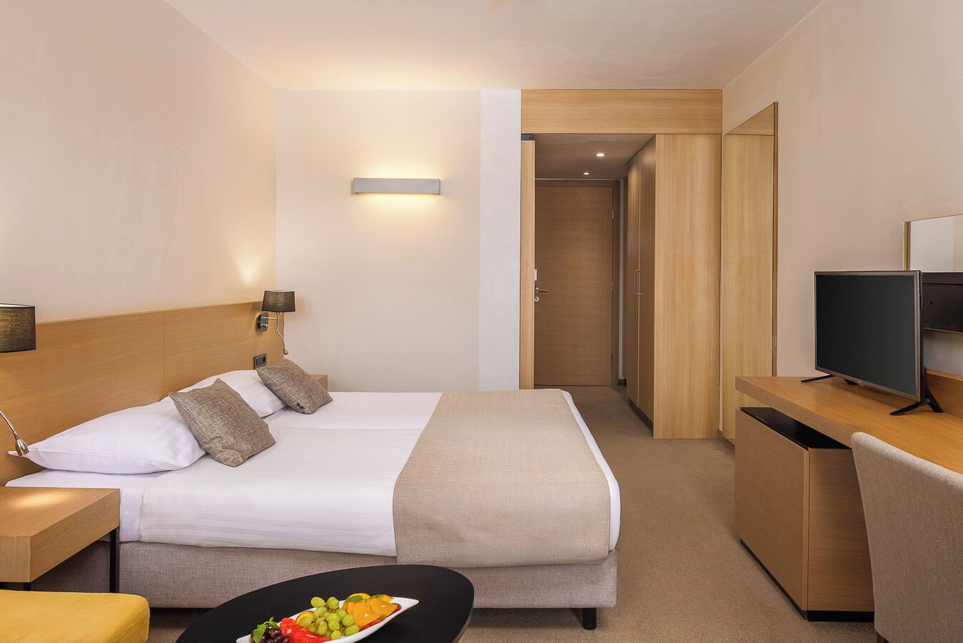 Habitación de hotel con cama, mesita de noche, televisión y escritorio con silla.