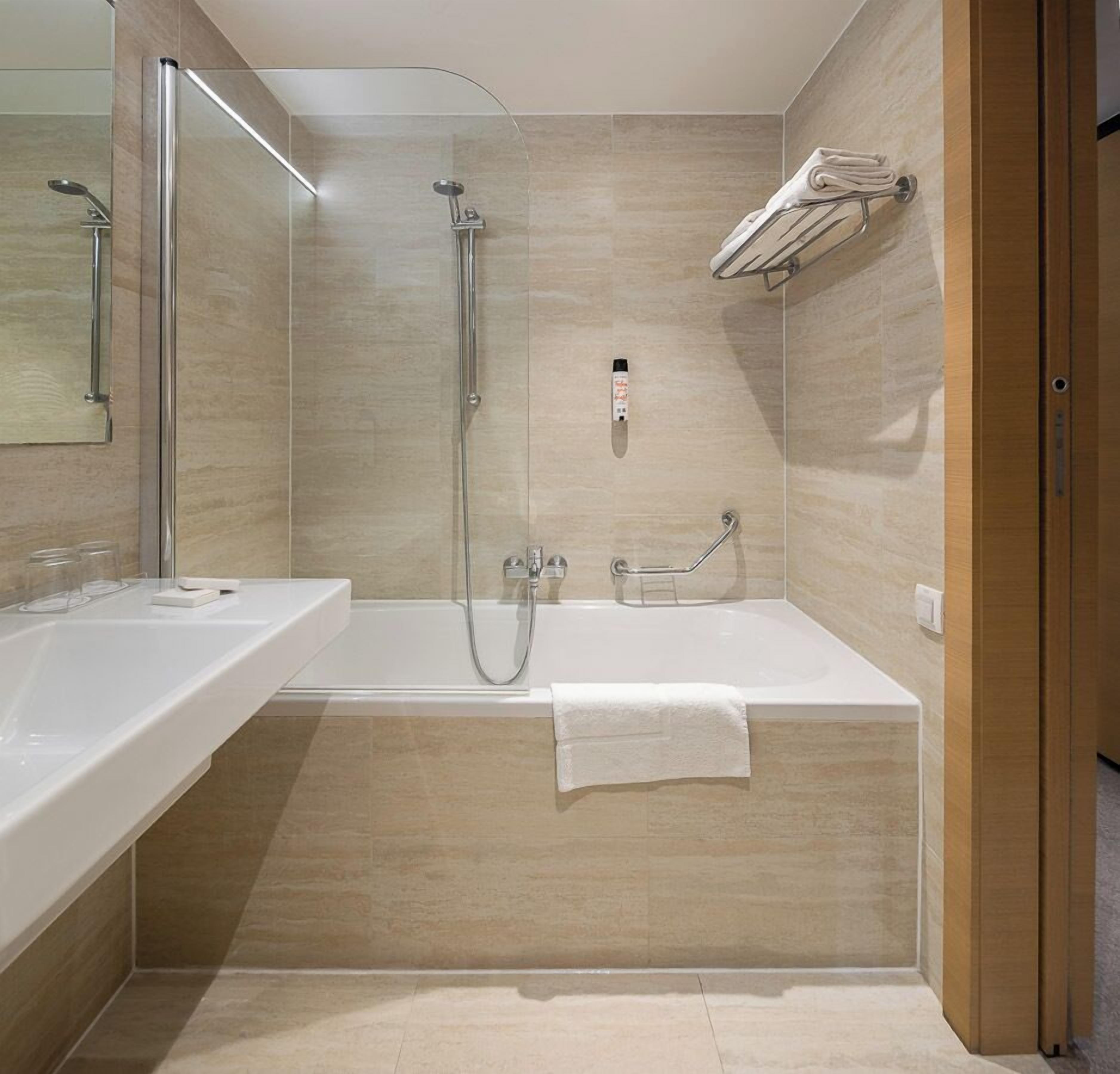 Un baño moderno con bañera, ducha y un perchero para toallas.