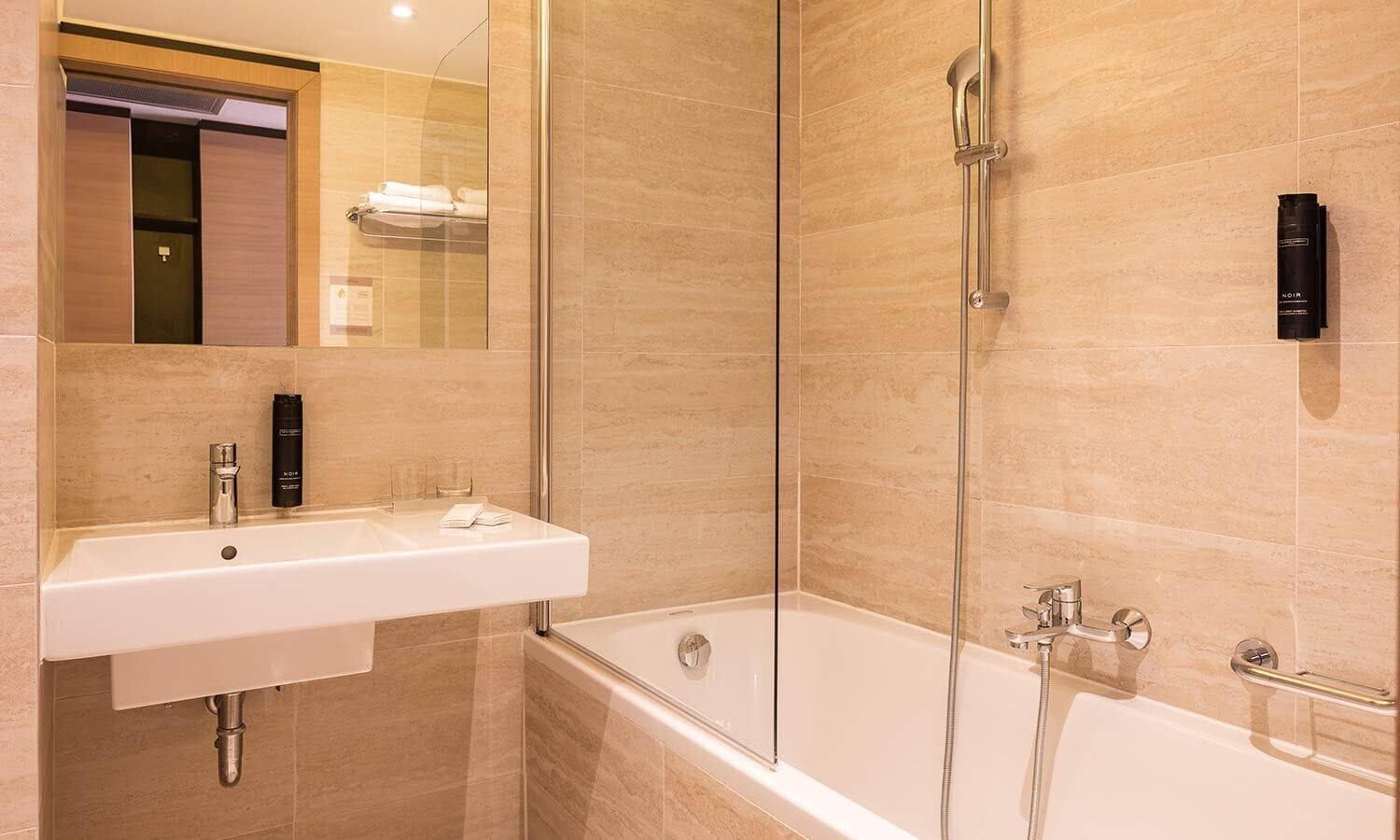 A modern bathroom with a glass-enclosed shower, a white sink, and a bathtub.