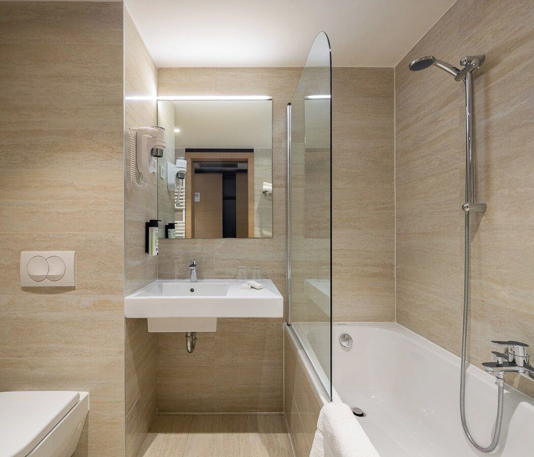 A modern bathroom with a glass-enclosed shower, a sink with a mirror, and a toilet.