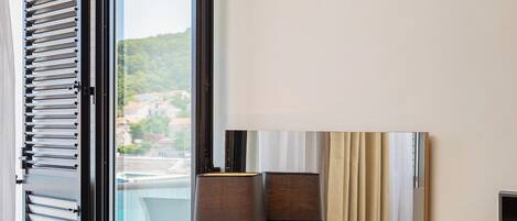 Une chambre d’hôtel équipée d’un bureau, d’une chaise et offrant une vue sur l’extérieur.