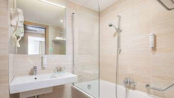Un baño moderno con ducha de vidrio, un lavamanos blanco y un espejo.