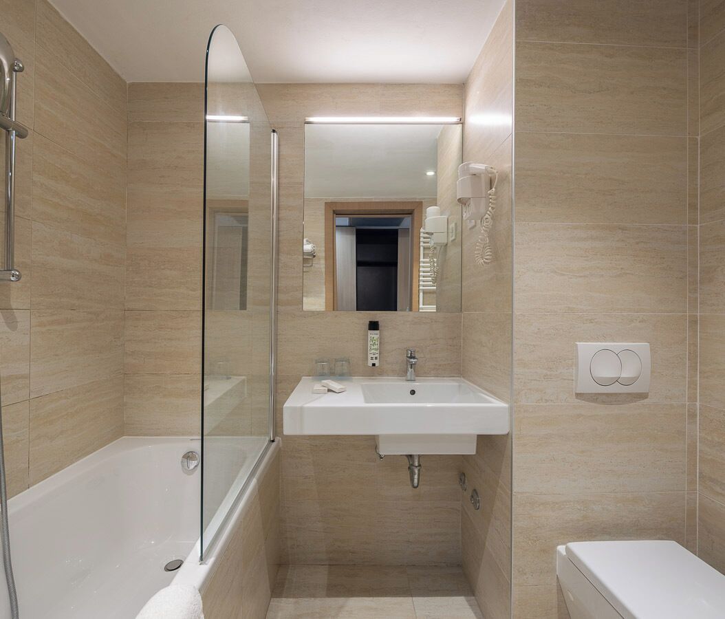 A modern bathroom with a glass shower enclosure, a white sink, and a toilet.