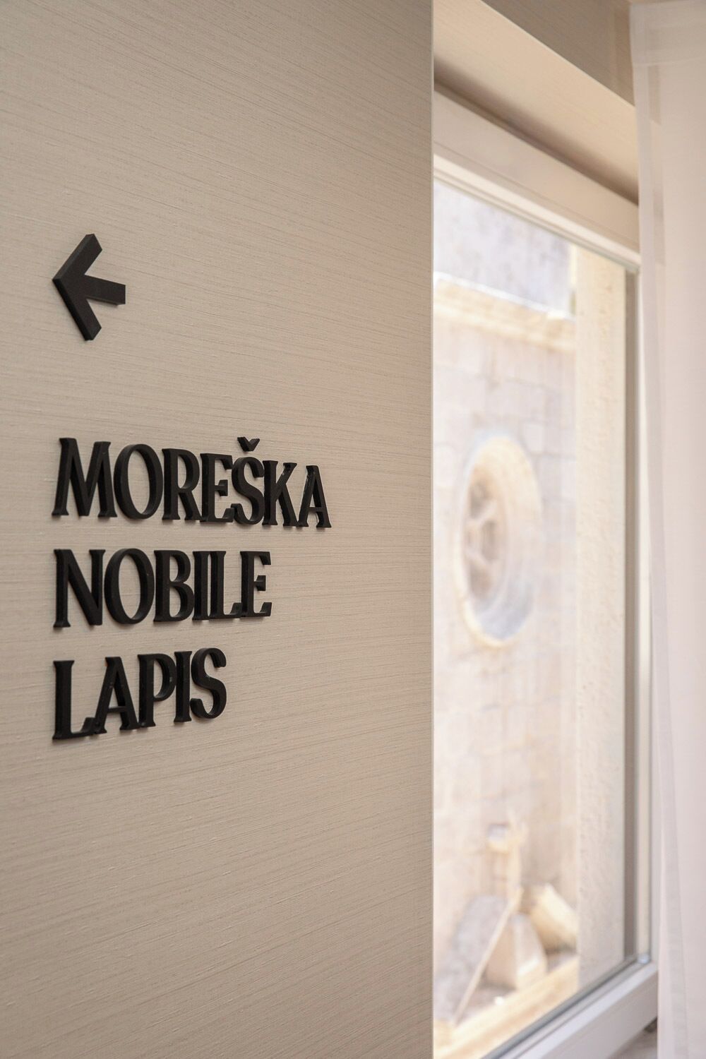 En væg med et skilt, der peger til venstre, og teksten 'MOREŠKA NOBILE LAPIS'.
