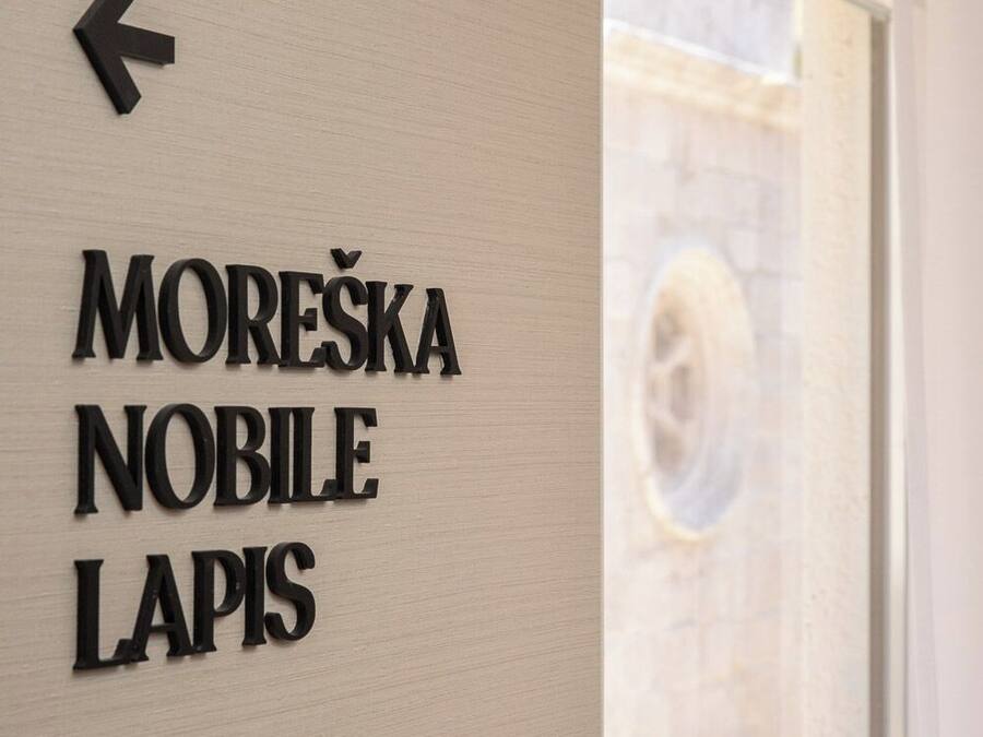 En væg med et skilt, der peger til venstre, og teksten 'MOREŠKA NOBILE LAPIS'.