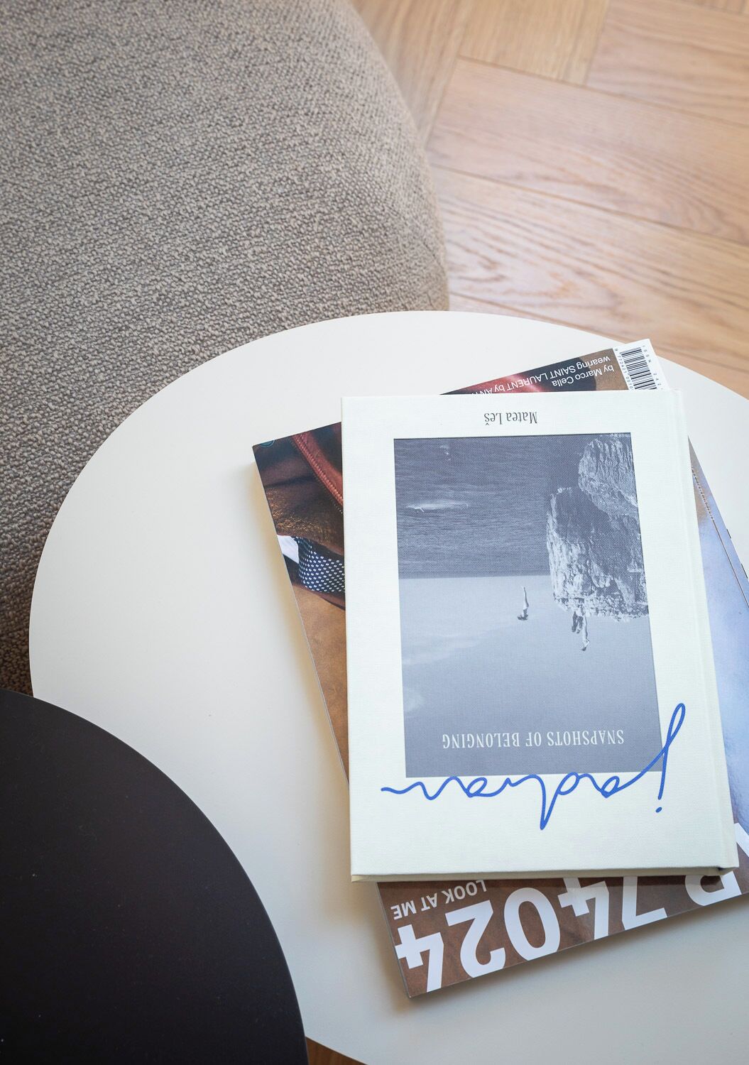A book titled 'Snapshots of Belonging' on a white table with a photograph on the cover.