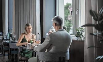 Un comedor con una mesa, sillas y un ventanal con cortinas.