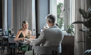 A dining area with a table, chairs, and a window with curtains.