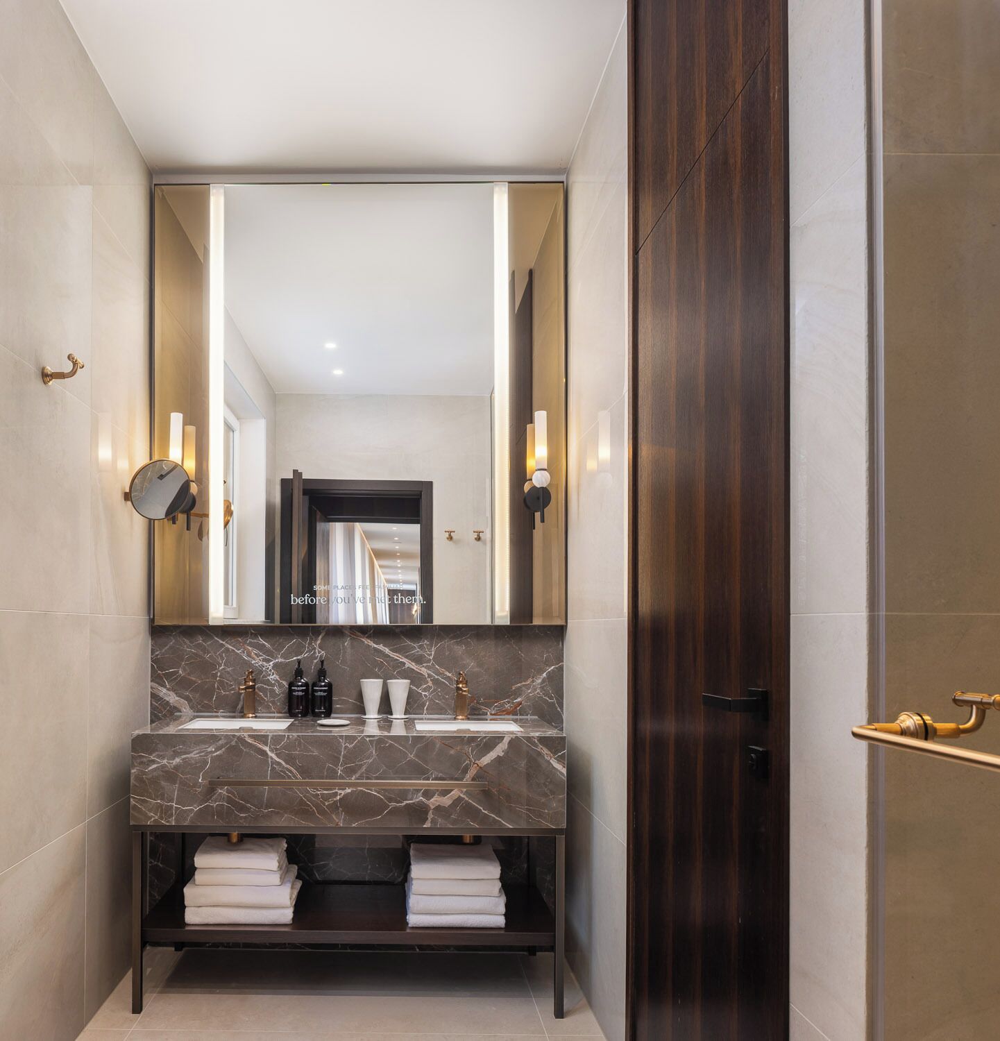 Un bagno moderno con lavabo in marmo, due luci a parete e un grande specchio.