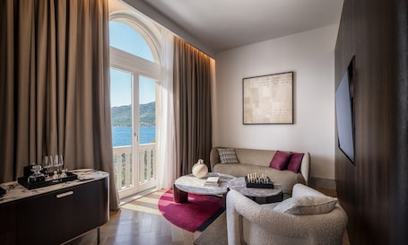 A hotel room with a balcony, a sofa, a coffee table, and a chess set.