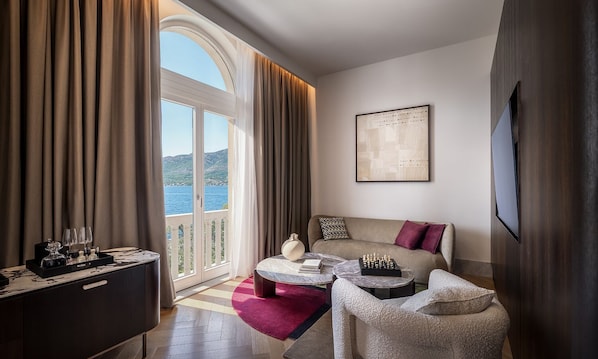A hotel room with a balcony, a sofa, a coffee table, and a chess set.