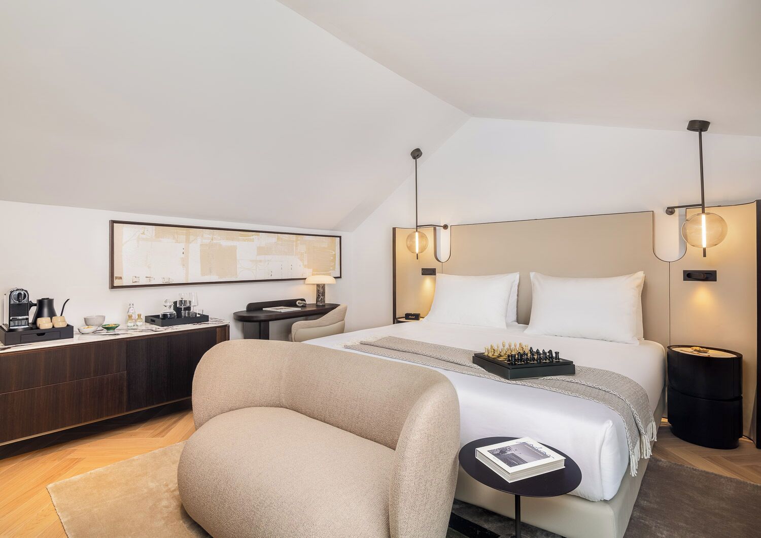 A modern hotel room with a bed, bedside tables, a desk, and a chair.