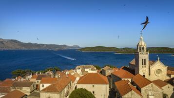 A coastal town with a prominent church tower, a boat on the sea, and a clear blue sky.