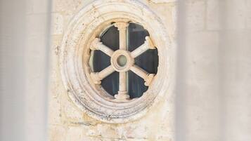A stone wall with a circular window featuring a cross at its base.