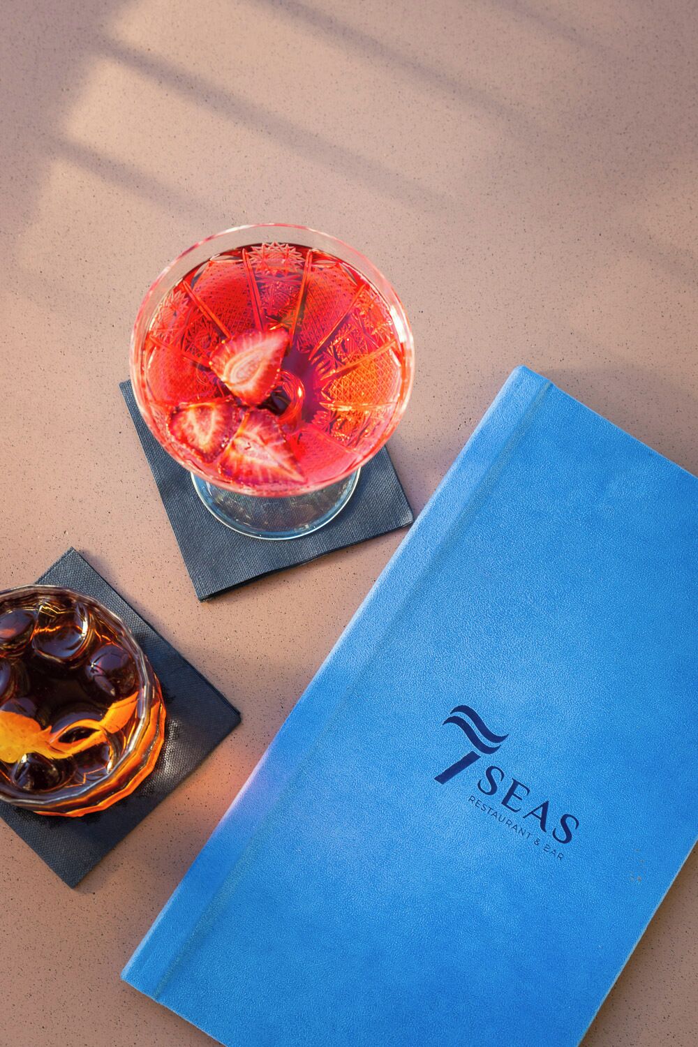 A blue menu and two glasses of beverages on a table.