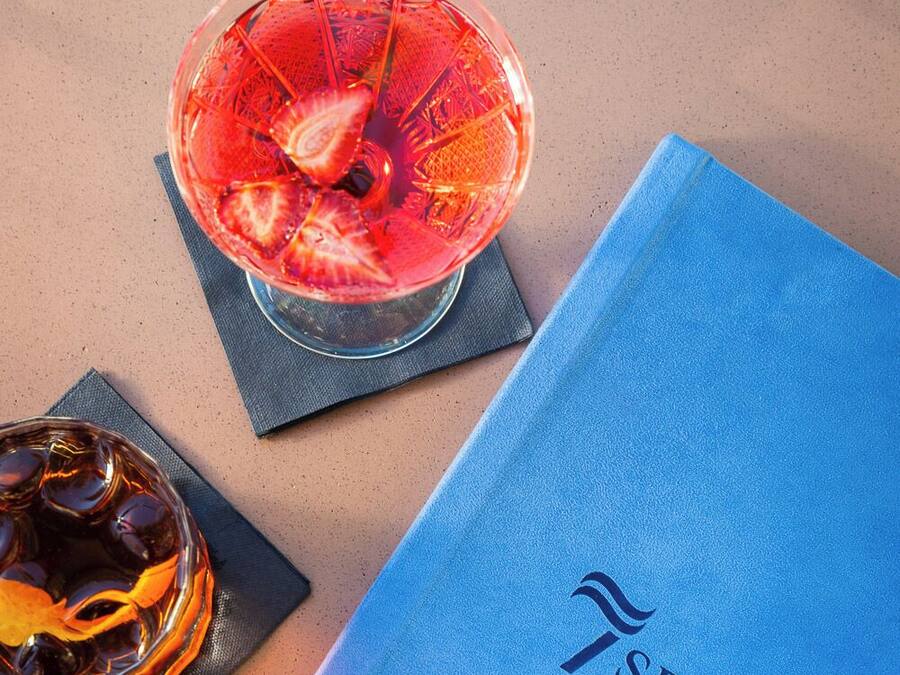 Un menu bleu et deux verres de boissons sur une table.