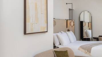 Habitación de hotel moderna con cama, sofá, una mesita con un libro, una obra de arte enmarco y una araña.