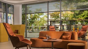 A modern living room with a sofa, chairs, and a coffee table. Large windows offer a view of the outdoors.