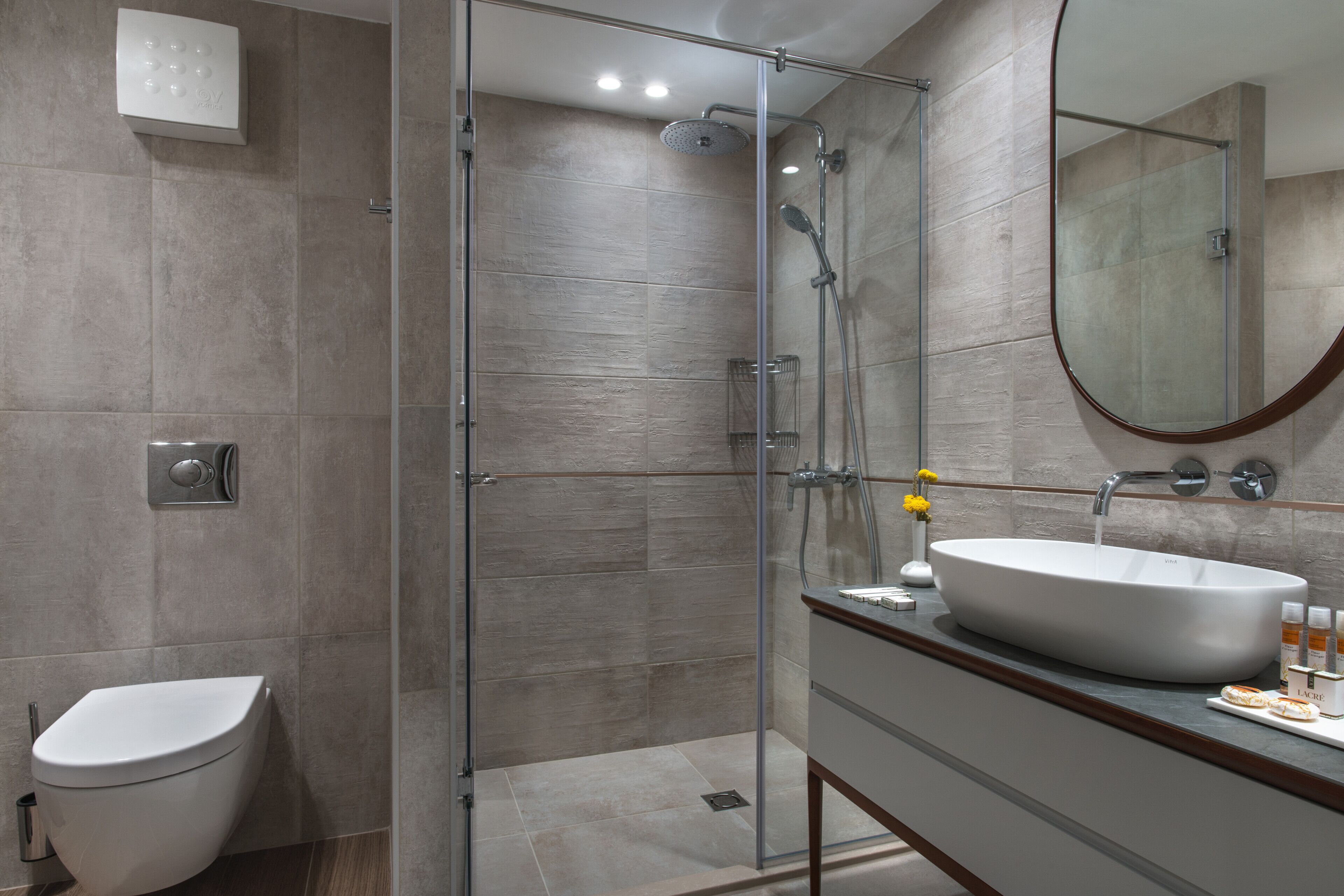A modern bathroom with a glass-enclosed shower, a white sink, and a toilet.