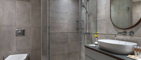 A modern bathroom with a glass-enclosed shower, a white sink, and a toilet.