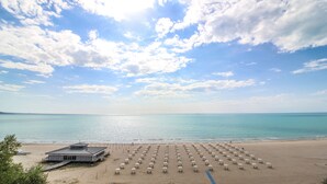 A beach with rows of umbrellas and a building with a flat roof.