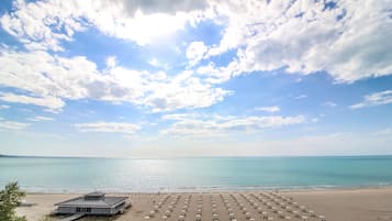 In Strandnähe, weißer Sandstrand, Liegestühle, Sonnenschirme