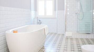A bathroom with a freestanding bathtub, a glass-enclosed shower, and a patterned floor.
