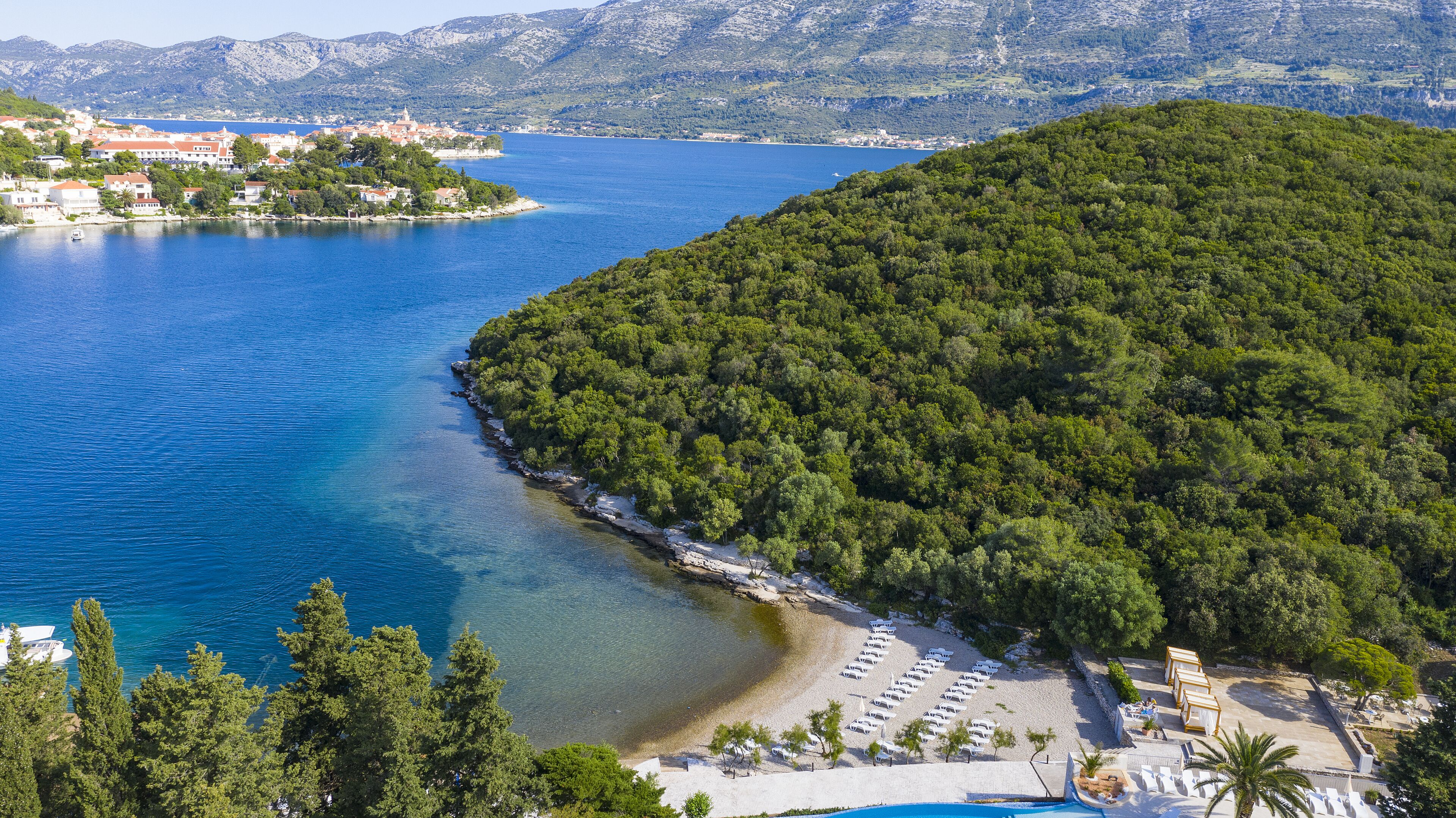 Une zone côtière comprenant une plage, une petite ville et une colline boisée.