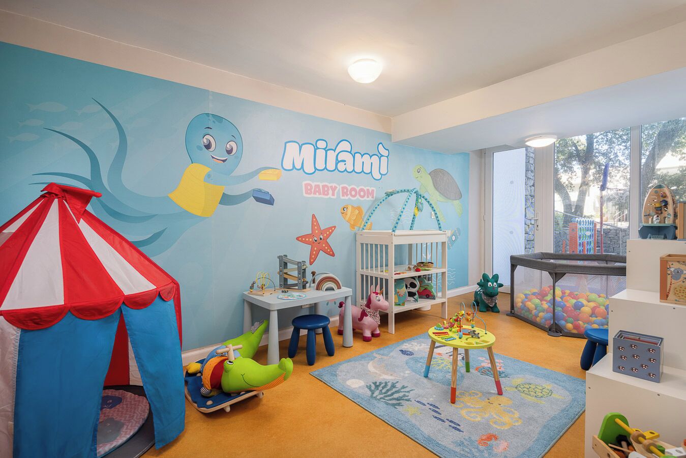 A baby room with a tent, play area, and a wall mural.