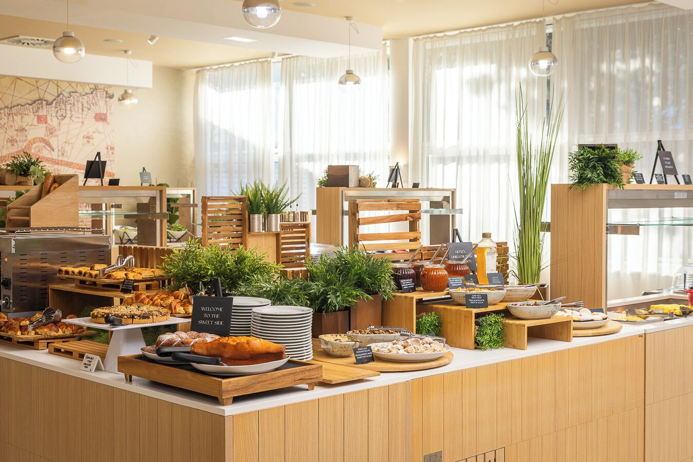 Ein Buffet mit verschiedenen Speisen, darunter Gebäck und Soßen, präsentiert auf einer Holztischplatte. Im Hintergrund ist eine Karte an der Wand zu sehen.