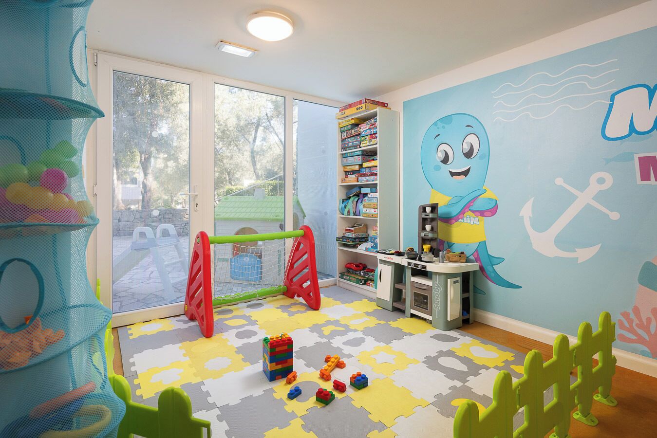 A child's playroom with a playhouse, toys, and a bookshelf.