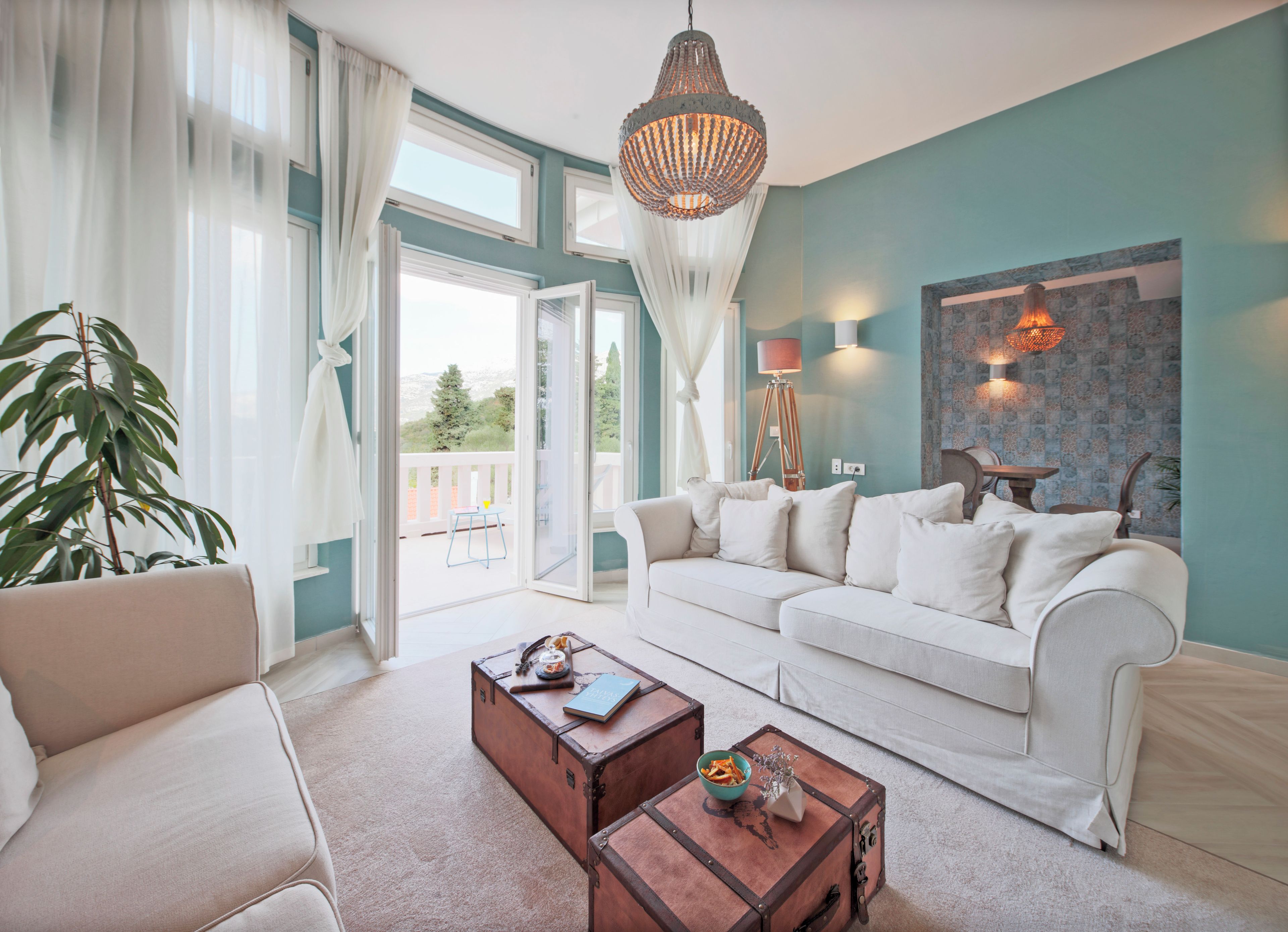 A living room with a sofa, a coffee table, and a large window with curtains.
